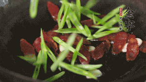 先后下香腸片、四季豆絲均勻翻炒，加適量清水燜煮一下。