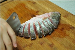 將鱸魚清洗干凈，從脊椎處切斷至腹部，腹部保留1cm左右不要切斷。