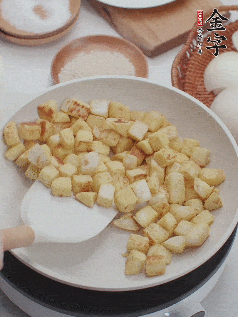 起鍋熱油，倒入饅頭丁，小火煎至蛋液凝固定型再翻面，饅頭丁部煎至金黃時(shí)盛起待用。
