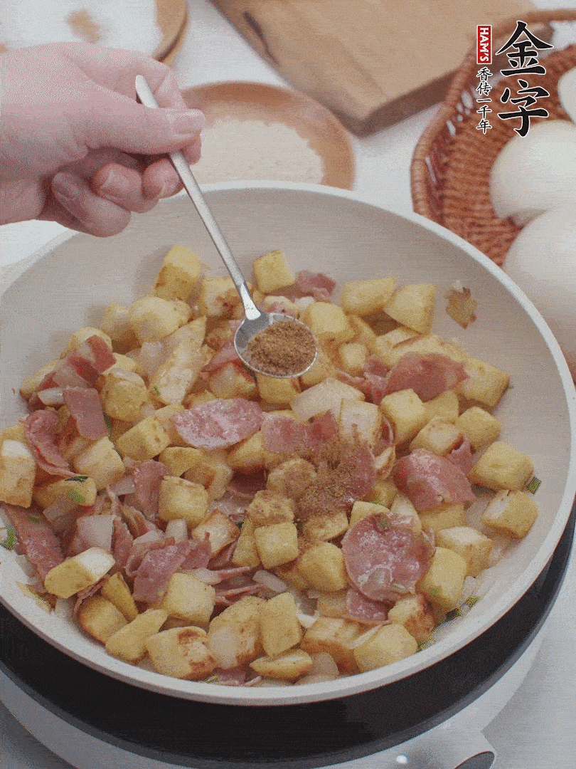 起鍋少油，煸香洋蔥丁、蔥白，加入金字培根火腿翻炒幾下，再加入饅頭丁、1小勺孜然粉、少許鹽翻炒均勻并鋪平。