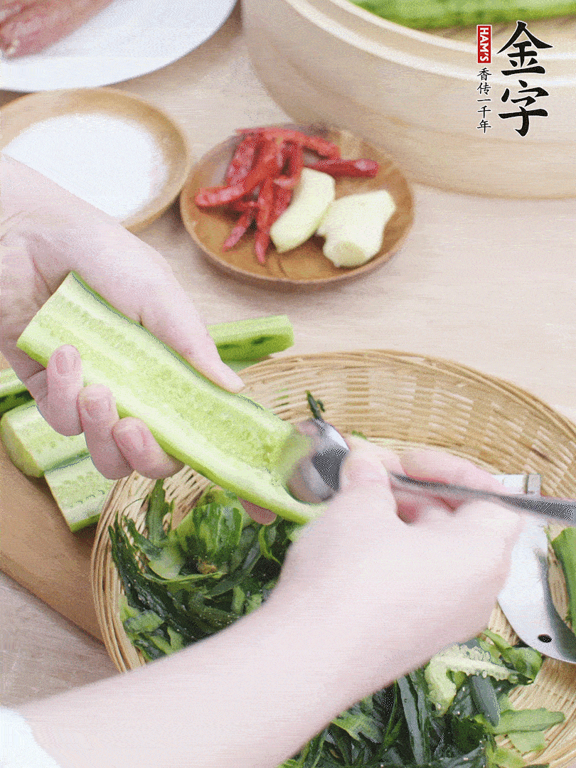 黃瓜削皮，對半切開，勺子挖去內(nèi)瓤，斜刀切片。青蒜斜刀切段。