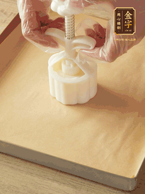 取一個面團，捏扁，中間厚，四周薄。虎口往上推，直到收口，把餅胚放入模具里，壓2-3下