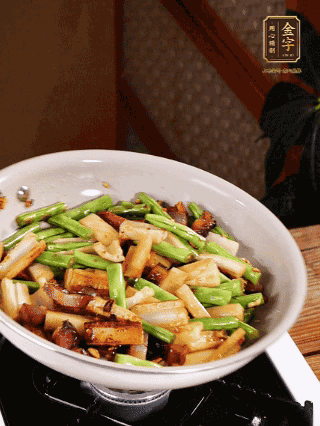 油熱下蒜末、干辣椒、醬肉煸炒出香味，依次下藕條、豆角翻炒均勻